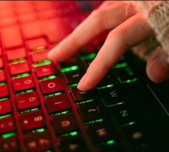 Close-up of a backlit keyboard with red and green lighting, representing urgent security patching