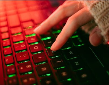 Close-up of a backlit keyboard with red and green lighting, representing urgent security patching