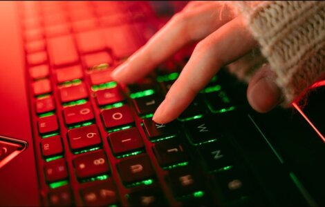 Close-up of a backlit keyboard with red and green lighting, representing urgent security patching