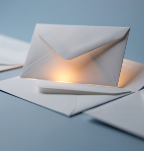 White envelopes on a soft blue surface, one lifted and highlighted