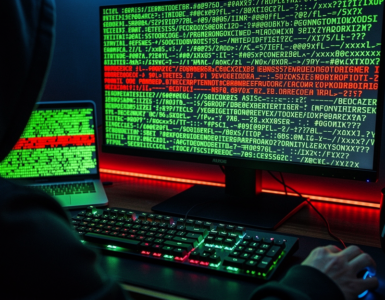 Hooded figure at a keyboard, monitor and laptop glowing with green terminal code, a line highlighted in red signifying an exploit