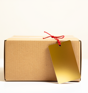 Plain cardboard box with an oversized blank gold price tag attached by a red string