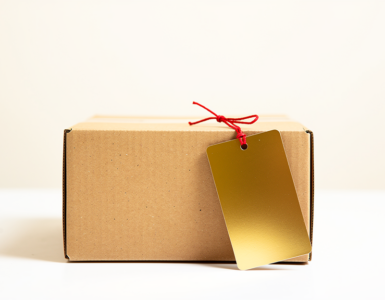 Plain cardboard box with an oversized blank gold price tag attached by a red string