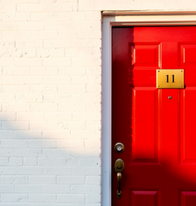 Bright red front door with brass number plate and a small Canadian flag