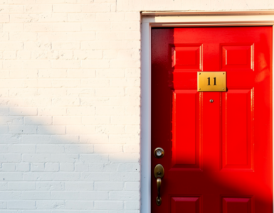 Bright red front door with brass number plate and a small Canadian flag
